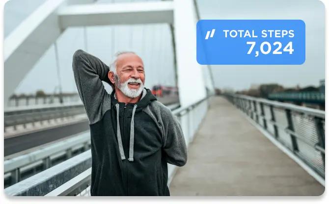 Older man in a sweatshirt stretching after jogging on the bridge.