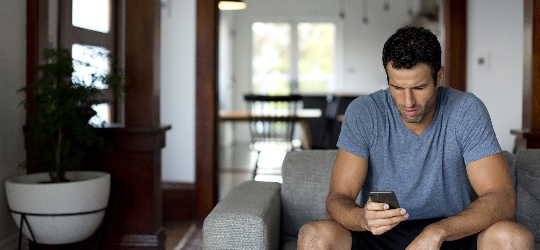 man looks at phone while sitting on couch