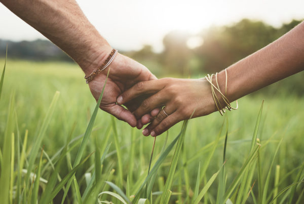 two people hold hands in a meadow of grass