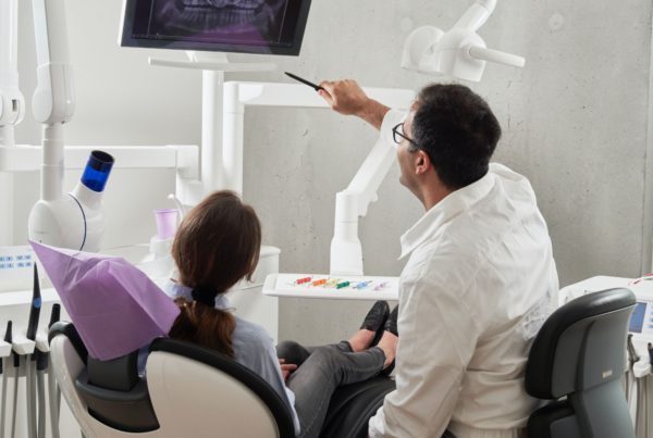 dentist showing patient an x-ray of her teeth in his office