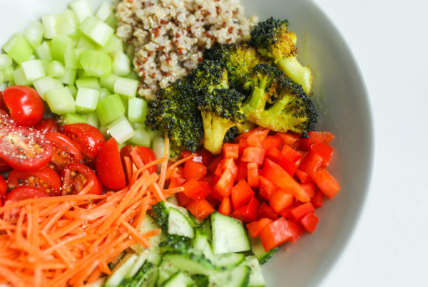 bowl of red peppers, broccoli, cucumbers, celery, tomatoes, carrots, and quinoa