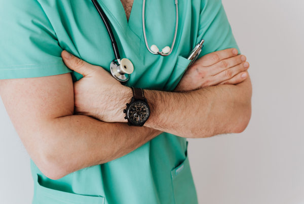 doctor in green scrubs standing with arms crossed
